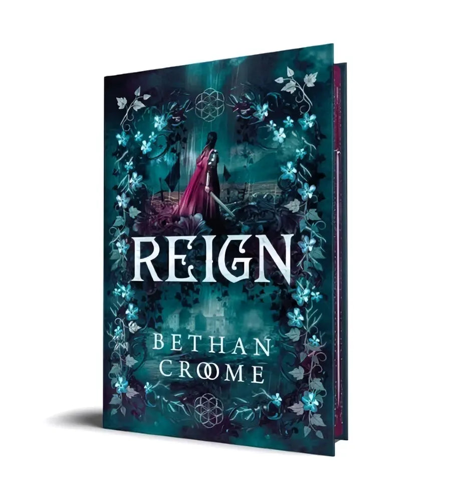 De deluxe edition van reign door bethany crome heeft een donker teal en zwarte cover met blauwe bloemmotieven en een figuur in een rode mantel voor romantische fantasy fans