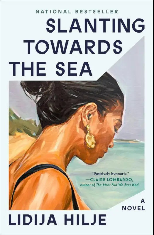 De boekcover van slanting towards the sea toont een schilderachtige vrouw met donkere knot en gouden oorringen tegen een strandachtergrond