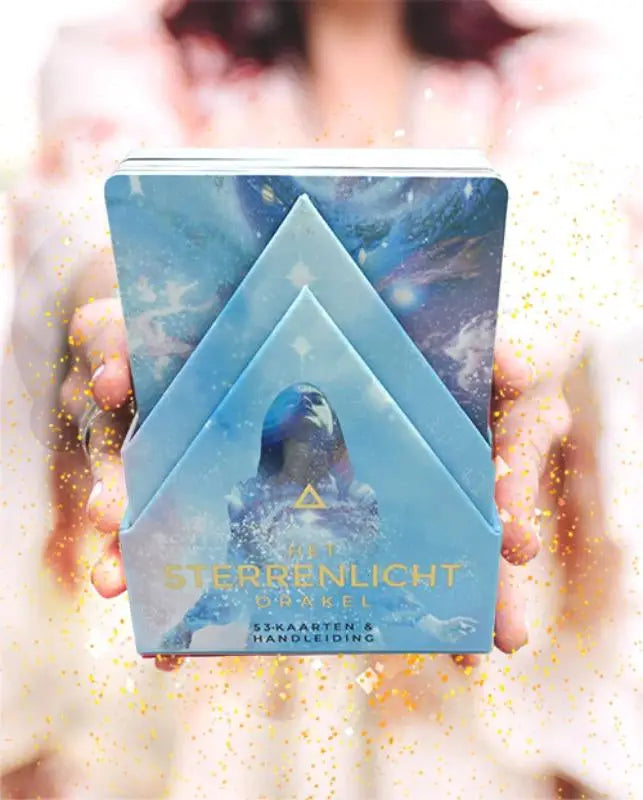 Een blauwe metalen doos met het sterrenlicht orakel tarotdeck van rebecca campbell, uitgegeven door koppenhol uitgeverij