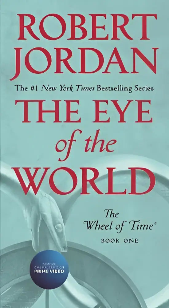 The eye of the world hardcover book one with red lettering on teal and hand holding a wheel illustration