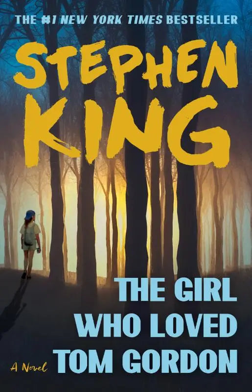 Paperback novel the girl who loved tom gordon by stephen king with bold yellow and blue text on moody forest cover