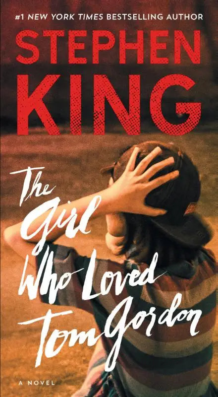 Boek the girl who loved tom gordon van stephen king met warme tinten en een kind in gestreept shirt en pet