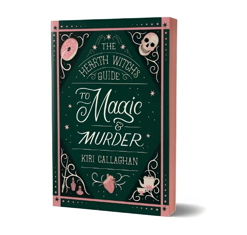 Dark green hardcover book with pink decorative borders titled the hearth witch’s guide to magic and murder by kiri gallagher