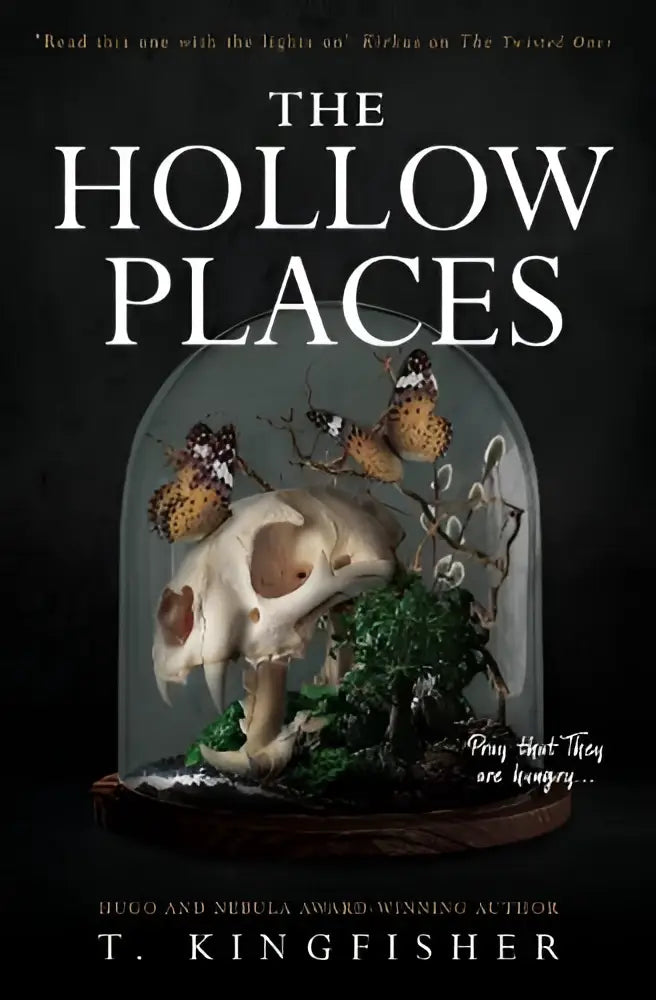 The hollow places boekomslag met een wit dierenschedel onder een glazen stolp omgeven door mos en bruine vlinders