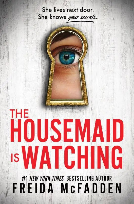 Een hardcover van the housemaid is watching van freida mcfadden met een gouden sleutelgatvormige lijst en een gedetailleerd blauw oog