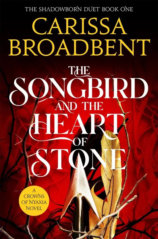 The songbird and the heart of stone boekomslag met rood achtergrond zwarte takken zilveren dolk en gouden veer