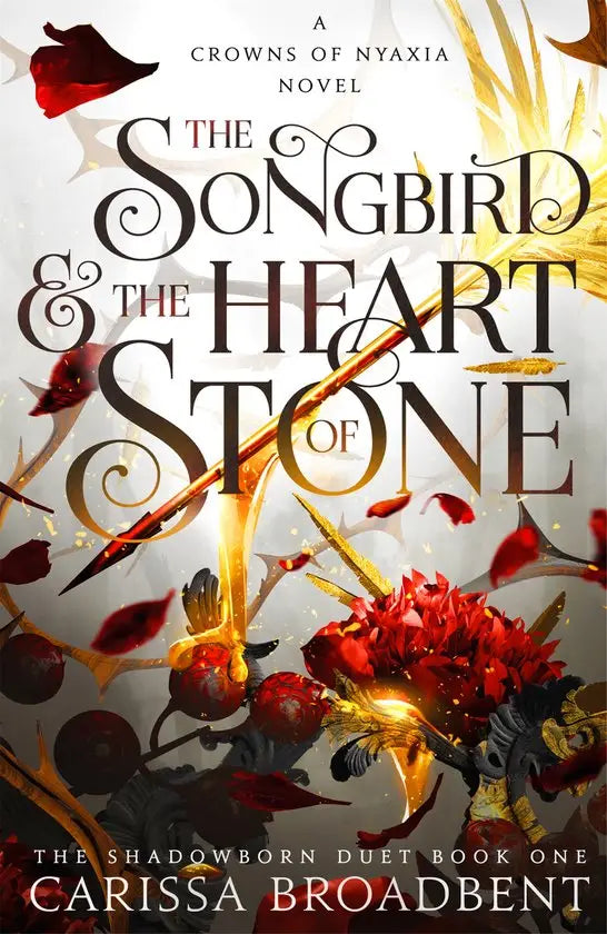 De hardback van the songbird and the heart of stone door carissa broadbent toont zwartgouden letters op een achtergrond van rode rozenblaadjes
