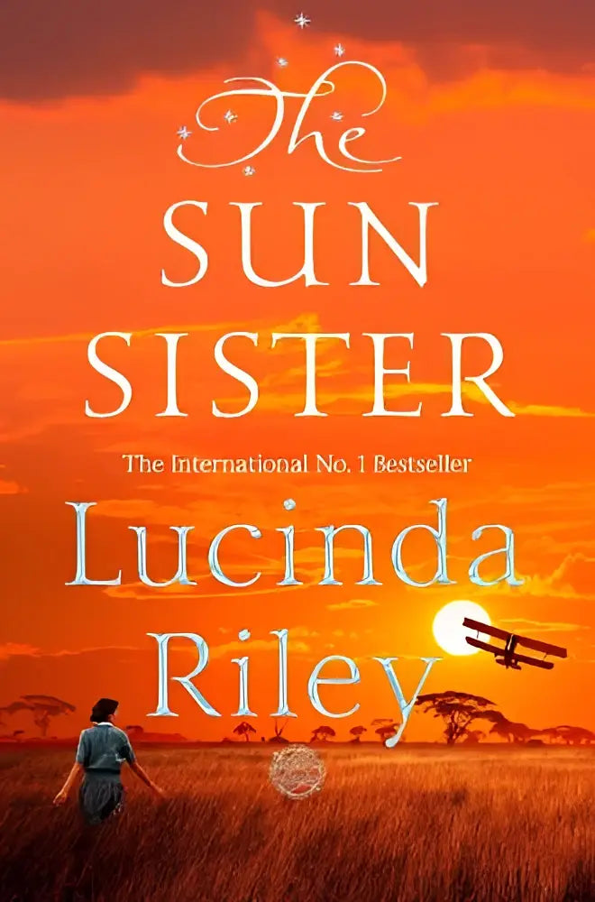 Paperback boek the sun sister van lucinda riley met oranje zonsondergang omslag en silhouetten van vrouw en tweedekker
