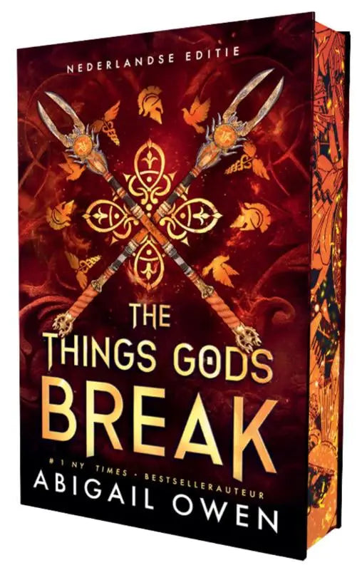 A hardcover edition of the things gods break with an ornate red and gold cover featuring crossed spears and intricate designs
