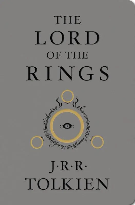 Grijs hardcoverboek the rings deluxe edition met zwarte letters en gouden ringontwerp van tolkien j.r.r