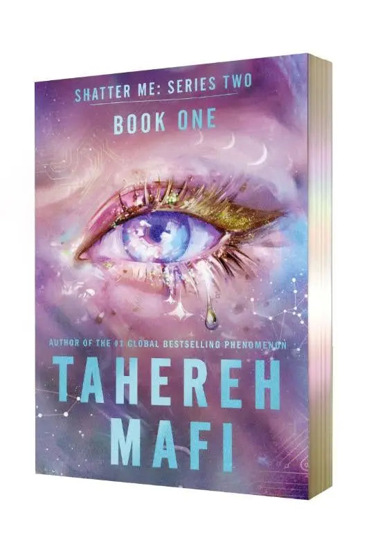A hardcover book with a purple and blue cosmic eye cover titled shatter me series two book one in paperback deluxe limited edition