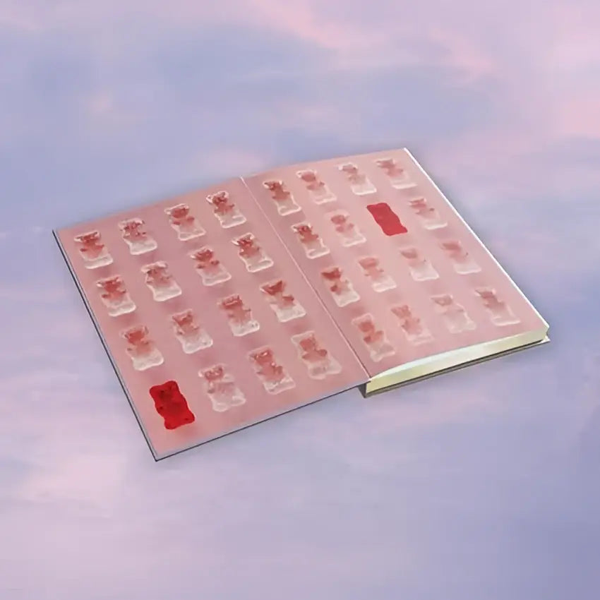 Een roze glanzend boek met rijtjes doorschijnende rode en heldere gummybeertjes stickers in the new republic editie