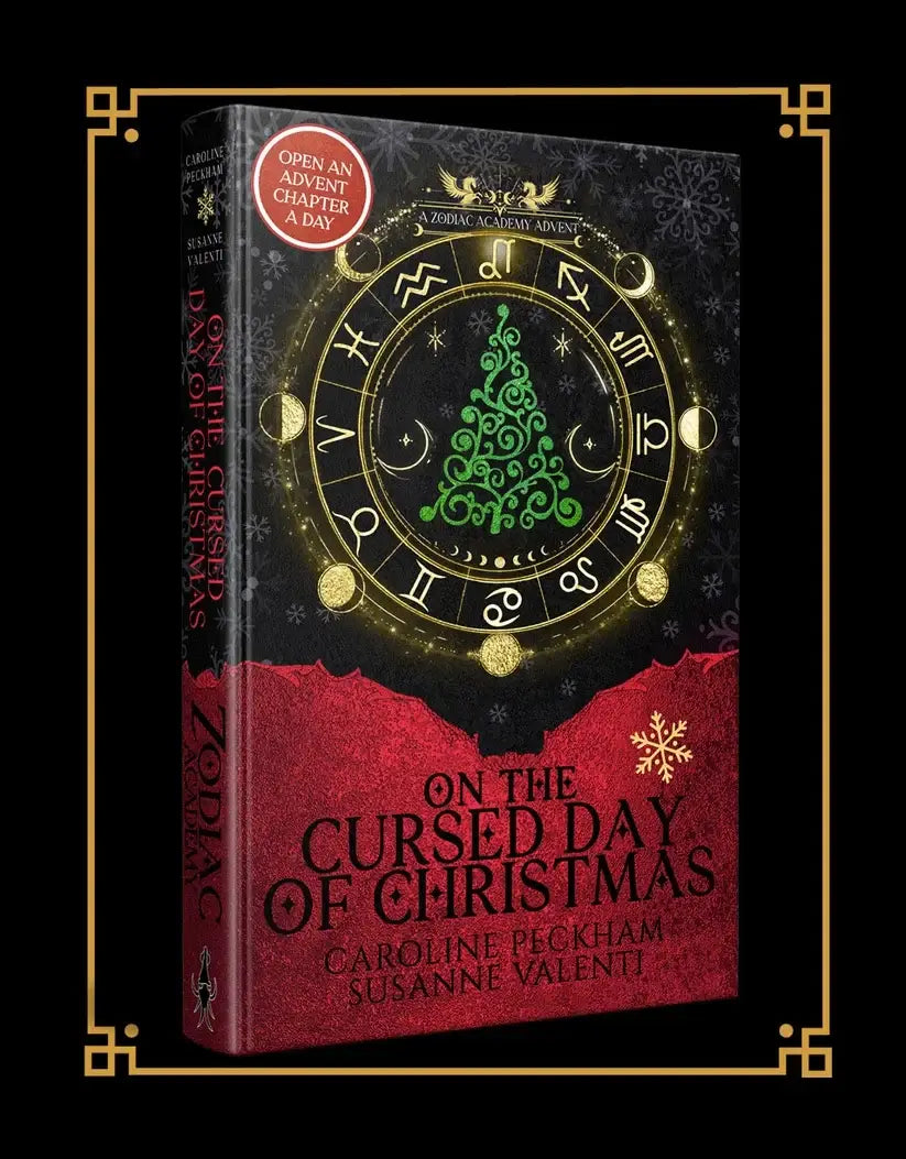 Zodiac academy hardcover boek met goudkleurig zodiakwiel en groene kerstboom op cover van the cursed day editie